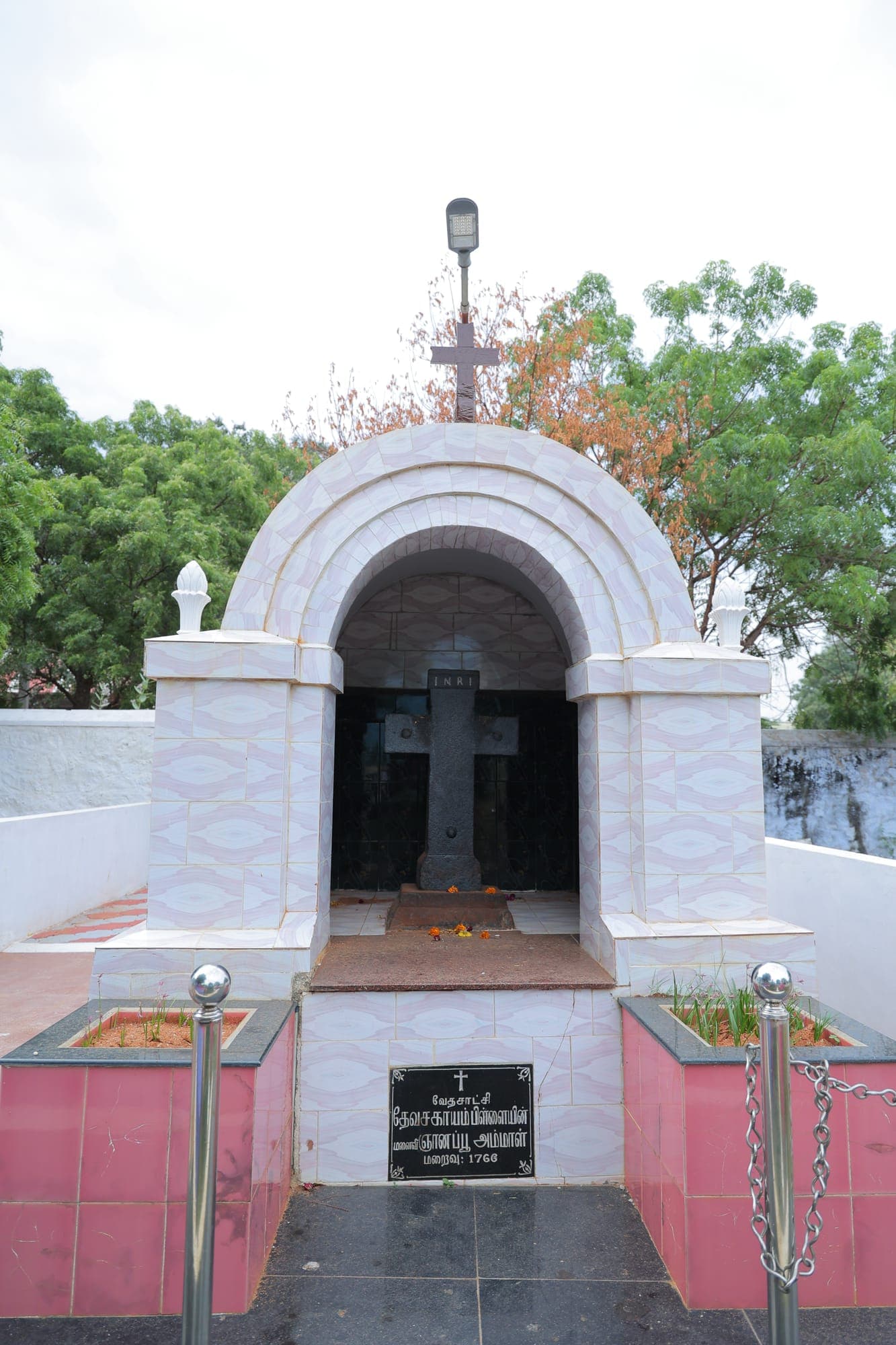 The tomb of Gnanapoo Ammal, who died in 1766, wife of St. Devasahayam Pillai, sheltered under a white arched memorial with a stone cross
