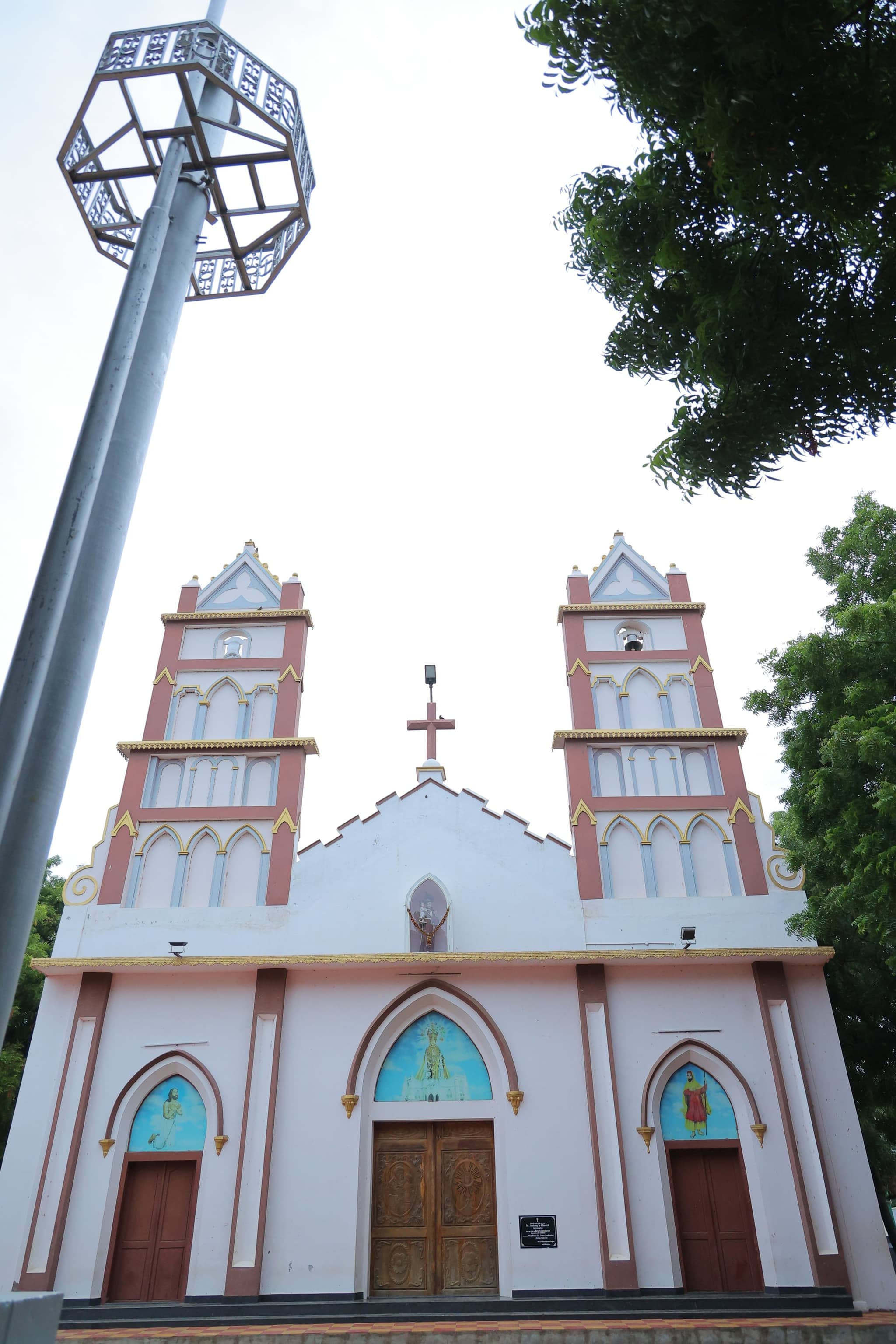 வடக்கன்குளம் புனித அந்தோணியார் ஆலயம் — இரு மெல்லிய கோபுரங்களுடன் இளஞ்சிவப்பு–வெள்ளை முகப்பு, அருகில் ஒரு விளக்குக் கம்பம்