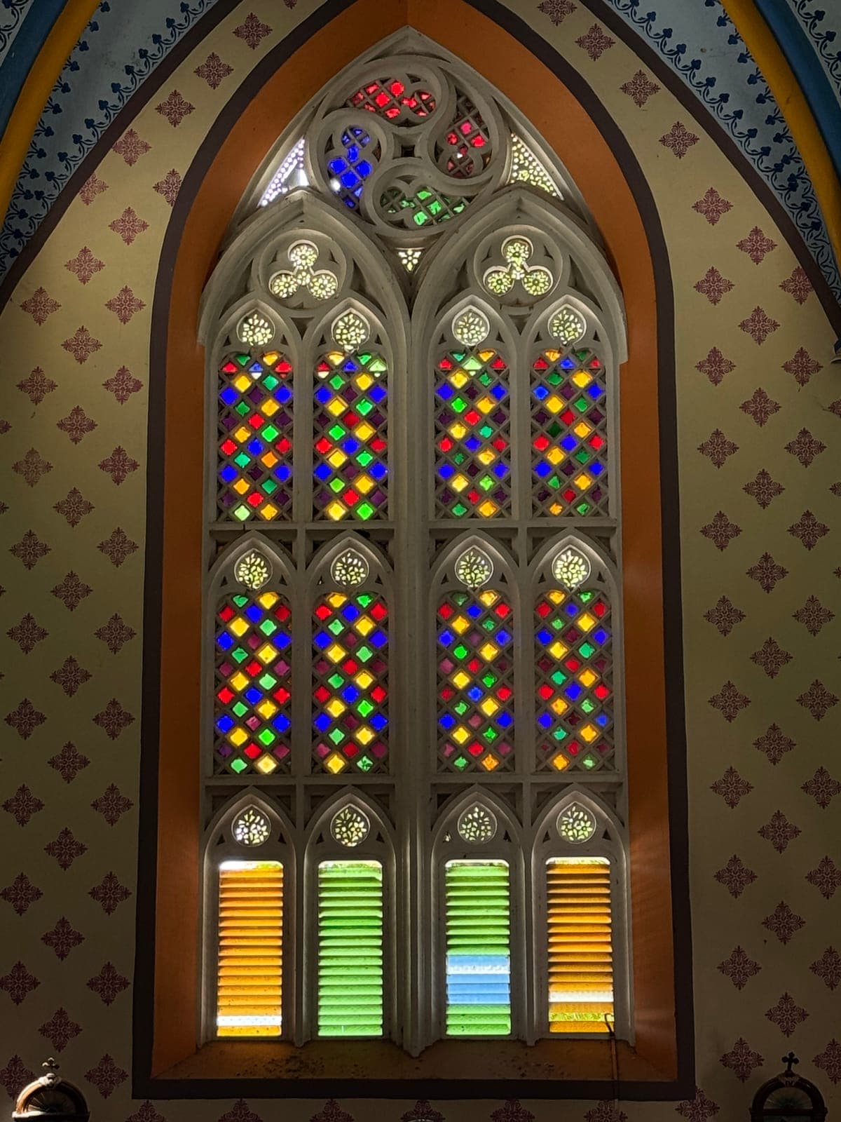 Coloured glass diamonds glowing in the plaster tracery of a nave window